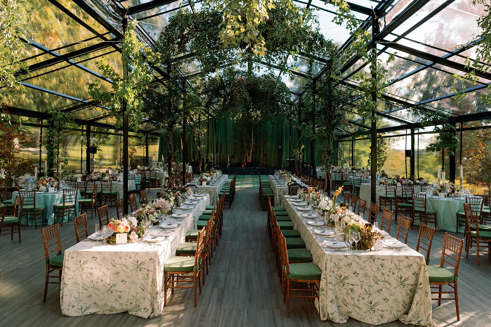 Intricately designed dinner tables set for a luxury private estate wedding in a greenhouse-style tent in Upstate New York.